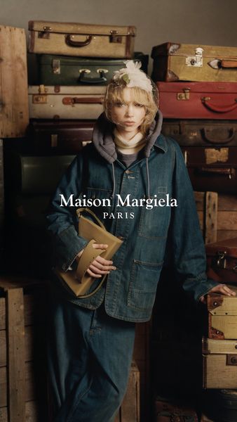 Poster Maison Margiela avec leur logo en premier plan, une dame avec des vêtement en jeans(veste et pantalon) entouré de valise vintage